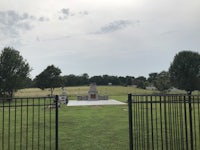 a fence with a gate in the middle of a grassy field