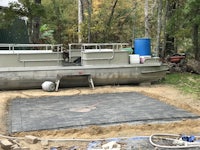 a boat is sitting on a concrete slab in a yard